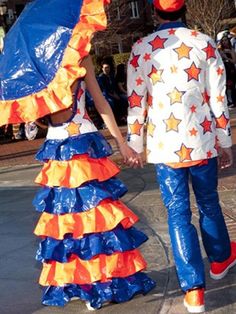 two people dressed in colorful clothing walking down the street