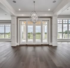 an empty living room with wood floors and french doors leading to the front door is shown