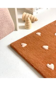 a brown rug with hearts on it next to a wooden toy and other items in the background