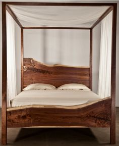 a wooden bed frame with white drapes on top