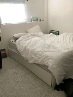 a person standing next to a bed with white sheets and pillows on top of it