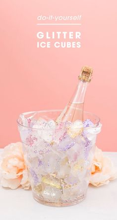 a bottle of champagne in a glass filled with ice cubes and gold flakes