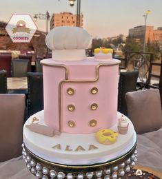 a pink and white cake sitting on top of a table