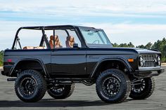 a black jeep with four seats in the middle of an empty parking lot on a sunny day