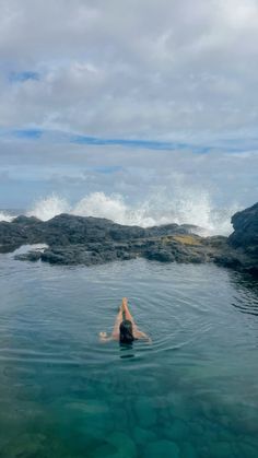 a person floating in the ocean with their arms up and head above water's surface