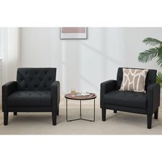 a living room with two chairs and a coffee table in front of a white wall