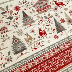 a red and white table cloth with reindeers, trees and snowflakes on it