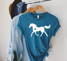 "Horse Love Shirt, Gift For Horse Owner, Farm Shirt, Horse Trainer Gift, Horses T-Shirt, Equestrian Horse Lover T shirt, Horse Mom Shirt Please Check All Photos For Details.   🐞Choose Your T-Shirt Size From The Drop-Down Lists Next To The item Picture   ⭐Choose Of Your T-Shirt Color From The 2nd Picture   🐞Use \"Add message to Seller\" link On The Checkout Page To Send me the Following important Details For Your Order's Customization.   ⭐Shipping Time Varies by location (we are located in Sugar Land, Texas) please consider that our turn around time is 1 to 3 business days.     ⭐Which brand do you use for t-shirts? We use Gildan Softstyle, Bella Canvas Unisex, Hanes, Outlash, Tees,  District and Next Level when we have a shortage of stocks for certain colors and sizes. Our printing method Casual Short Sleeve Tops With Horse Design, Short Sleeve Cotton Top With Horse Design, Cotton Short Sleeve Top With Horse Design, Horse Trainer Gifts, Cricut Jewelry, Man On Horse, Horse Trainer, Sugar Land, Horse Owner