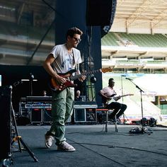 a man playing guitar on stage in front of microphones