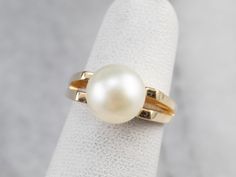 This gorgeous vintage piece is crafted of sleek yellow gold that features a perfect polish. Utterly simple, this vintage piece features a single, modestly sized pearl framed by sleek open-work shoulders. Metal: 14K Yellow Gold Gem: Pearl Gem Measurements: 8.3 mm, Round Ring Size: 3.25 Marks: "CGW14K" Stamped on the inside band Classic Yellow Gold Pearl Ring With Round Band, Classic Pearl Ring For Wedding, Classic Wedding Pearl Ring, Classic Pearl Drop Ring, Gold Solitaire Pearl Ring Timeless Style, Classic Oval Solitaire Pearl Ring, Elegant Yellow Gold Solitaire Pearl Ring, Classic 14k Gold Pearl Ring, Classic 14k Gold Solitaire Pearl Ring