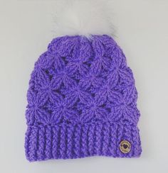 a purple knitted beanie with a white fur pom