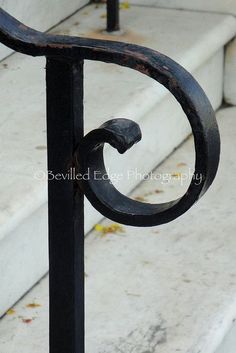 an iron hand rail on the side of a building with steps in the back ground