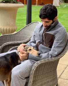 a man sitting on a chair next to a dog