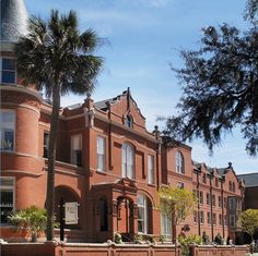 an old red brick building with a tower and palm trees in the foreground on a sunny day