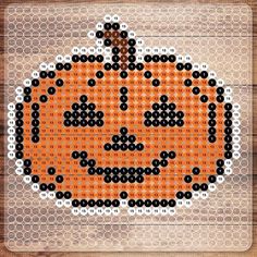 a cross stitch pumpkin sitting on top of a wooden table