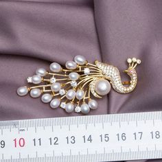 ORIGINAL DESIGNED: Round peacock Pearl Lapel Pin Brooch; designed by nature-originated jewelry designer in the team 1950s VINTAGE STYLE: the brooches creates a sense of 1950s and brings you antique fashion looking DETAILS: ornamented with pearls and crystal, the pins are young, shining, and easy to maintain, Freshwater pearl. STYLES: 3 SIZE: 80 x 40 mm A must-have in your wardrobe essentials! Wear it casually with your linen blazer or even to an important event Add an element of style and color Elegant Peacock-colored Brooches For Wedding, Elegant Peacock Brooches For Wedding, Elegant Peacock Design Brooch For Formal Occasions, Elegant Peacock Design Brooch For Formal Wear, Elegant Peacock Color Wedding Brooches, Elegant Wedding Brooch With Peacock Design, Gold Brooches With Peacock Design As Gift, Elegant Peacock Design Brooch For Wedding, Elegant Peacock Design Wedding Brooch