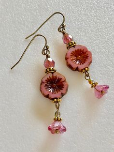 "Lovely little pink dangles featuring 15 mm pink Czech glass Hawaiian flowers with rustic Picasso glaze, 6 x9 mm fuchsia pink Czech bellflowers with copper, and 6 mm pink/gold fire polished crystal rondelles. Czech beads are accented with antique gold beaded spacers and daisies. Vintage bronze French ear hooks. Total drop 2\"." Vintage Things Aesthetic, Hawaiian Aesthetic Outfit, Pink And Gold Earrings, Flower Clothes, Glass Flower Earrings, Pink Flower Earrings, Earring Beads, Flowers Earrings, Pink Jewels