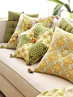 a couch with many pillows on it in front of a potted plant and window