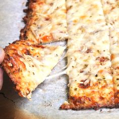 a person holding up a slice of pizza with cheese on it's crusts