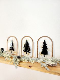 three wooden christmas trees on a mantle with pine cones