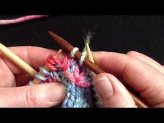 two hands are holding knitting needles and yarn