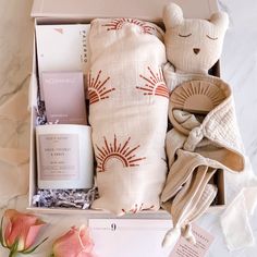 an open box with items inside on a marble counter top next to pink flowers and candles