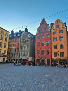 people are walking around in front of some buildings on a cobblestone street,