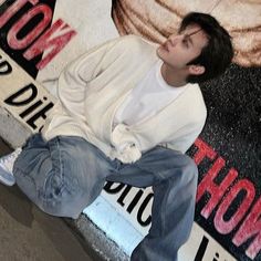 a young man sitting on the side of a wall next to a sign that says hollywood