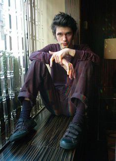 a man sitting on top of a wooden floor next to a glass window sill