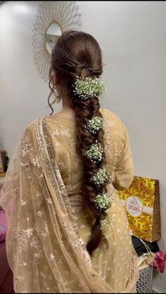 a woman with long hair and flowers in her hair, wearing a yellow sari