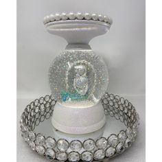 a snow globe is sitting on top of a stand with pearls and beads around it