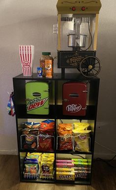 a shelf filled with lots of food next to a popcorn dispenser on top of a hard wood floor