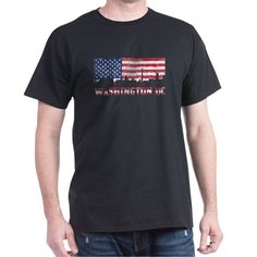 a man wearing a black t - shirt with an american flag and mountains in the background