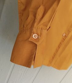 "VERY rare label...searches come up with NOTHING! I am quite sure this is a deadstock item. I bought it about 30 years ago, and have been too lazy to press it, so it just sat in a box until now. I can best describe the color as a mustard or very deep pumpkin. NO FLAWS! The tailoring is magnificent, with pleated sleeves, and turn up cuffs that expose the button, not to mention the iconic Rockabilly collar of the 1950s. The 12 on the collar, I believe indicates the age of the wearer: 12! Bust is 3 Retro Solid Color Shirt With Button Closure, Mustard Retro Long Sleeve Tops, Yellow Retro Shirt With Buttons, Retro Yellow Button-up Blouse, Vintage Yellow Collared Blouse, Pleated Sleeves, Girls Blouse, Thing 1 Thing 2, Mustard