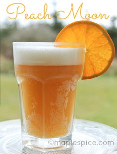 an orange slice is sitting next to a glass of beer on a table with the caption peach moon