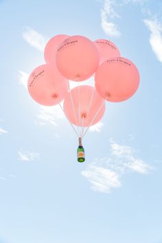 a bunch of balloons floating in the air with a bottle attached to one of them