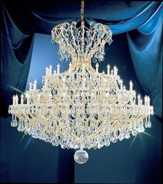 a large crystal chandelier hanging from the ceiling in a room with blue curtains