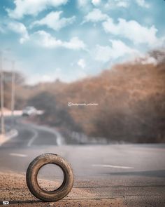 an old tire sitting on the side of a road in front of a cloudy sky