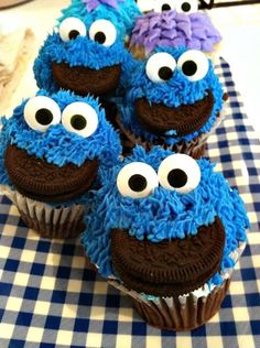 cupcakes with blue frosting and googly eyes are on a checkered tablecloth