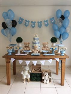 a table topped with lots of blue and white balloons next to a cake on top of a wooden table