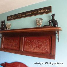 there is a shelf above the bed with two cats on it and another cat figurine next to it