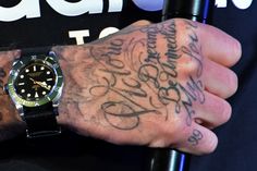 a man with tattoos on his arm and wrist is holding onto a black watch band