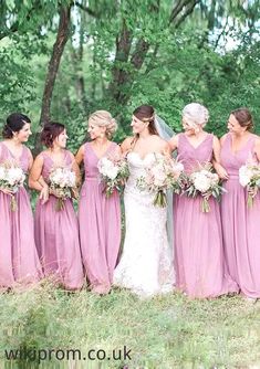 a group of women standing next to each other in front of some trees and grass