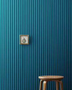 a wooden stool sitting in front of a blue wall