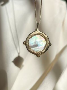 A dreamy 15mm hand-carved Mother of Pearl Moon encircled in gold, set with (4) White Diamonds, set on a solid 14k yellow gold 0.8mm box chain. (Approx. 5.7g.) Inspired in essence by the Impressionist French composer Claude Debussy, Clair de Lune translates to pale blue light or moonlight, and embodies the Divine Feminine energy of the moon, wholly encapsulating the deep sense of serenity found through inner self-awareness, and the strength kept within the gentleness of the heart. Aligns with int Spiritual Recycled Gold Round Pendant Jewelry, Hand Forged Fine Jewelry, Celestial 14k Gold Round Pendant Jewelry, Unique Round Pearl Pendant Jewelry, Recycled Gold Coin Pendant Jewelry Gift, Sterling Silver Medallion With Pearl Pendant, Heirloom Style Pearl Pendant Jewelry Gift, Spiritual Recycled Gold Jewelry, Recycled Gold Spiritual Jewelry