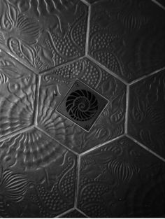 a black and white photo of a tile wall with an image of a spiral design on it