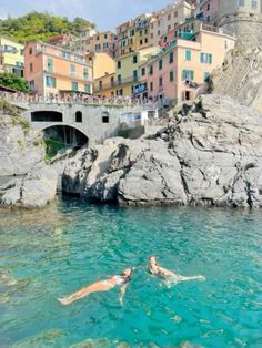 two people swimming in the water near some buildings