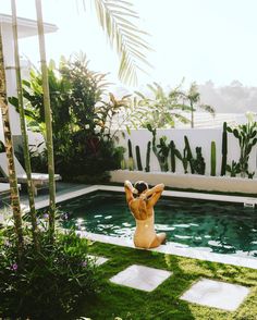 an inflatable person is sitting on the grass near a swimming pool and palm trees