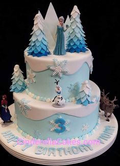 there is a cake decorated with frosting and decorations on the top, along with characters from frozen world