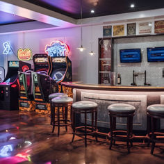 a bar with stools in front of it and several video games on the wall